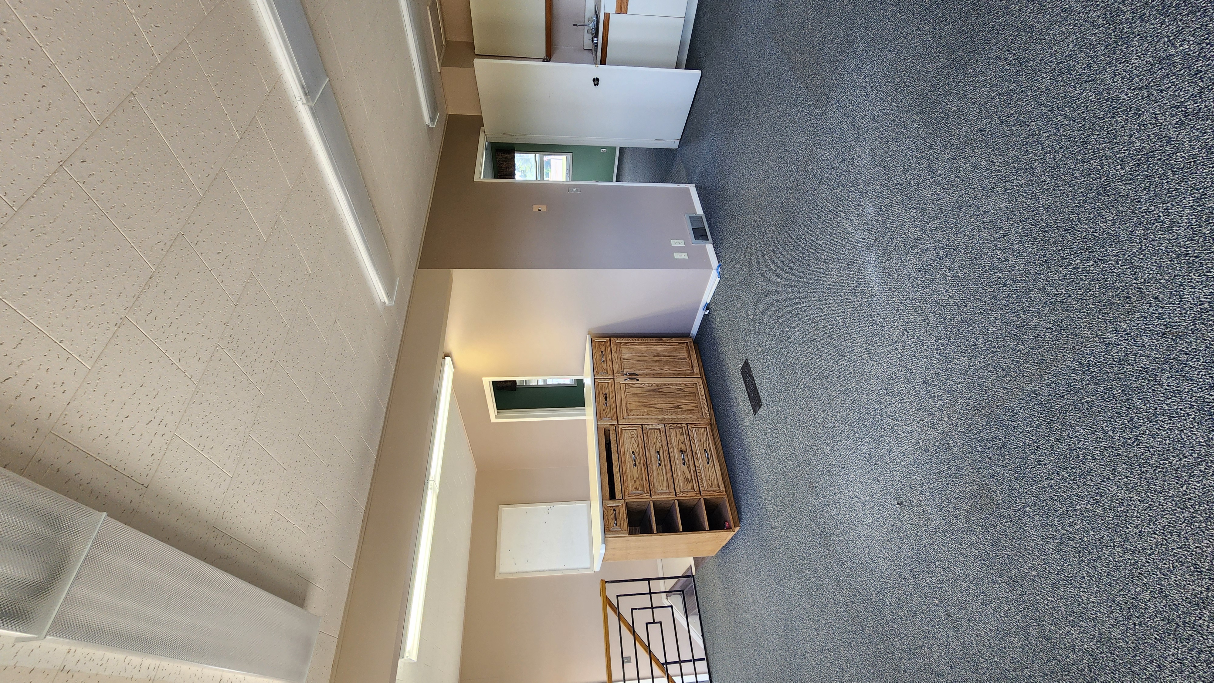 Interior picture of an office building with brown walls, an oak welcome desk, and blue carpet