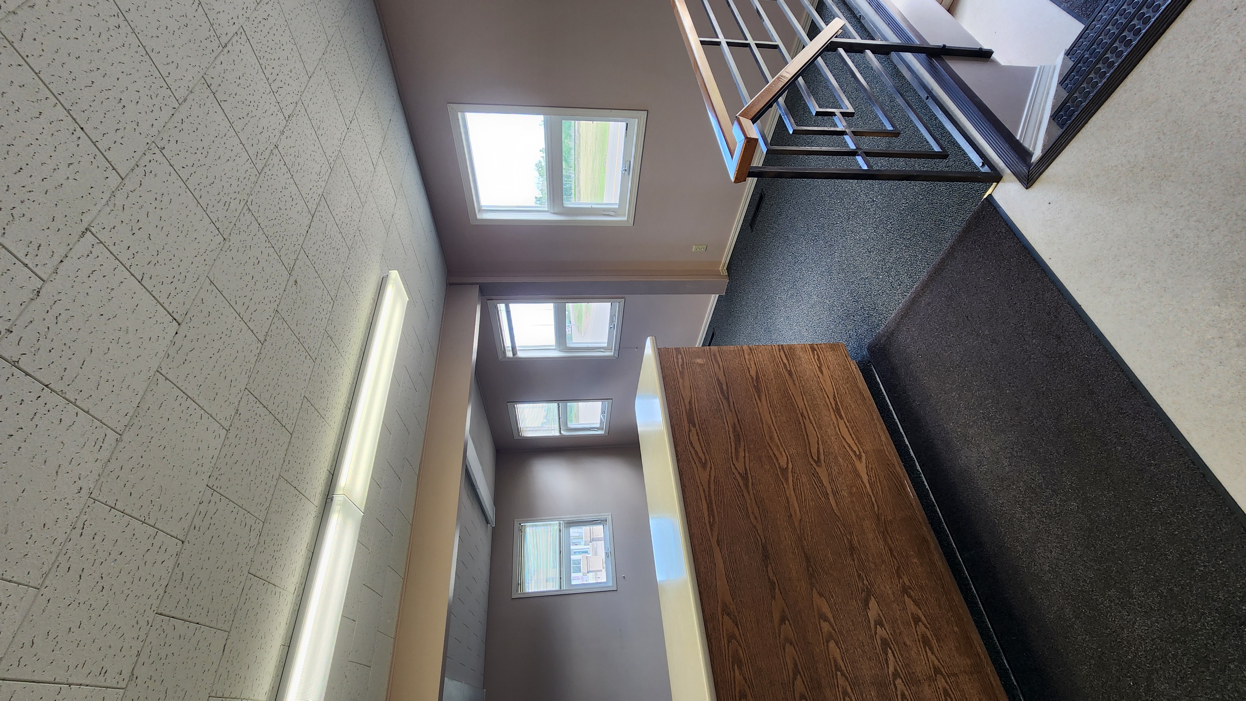 Inside of commercial office building with brown walls, wood desk and bright windows