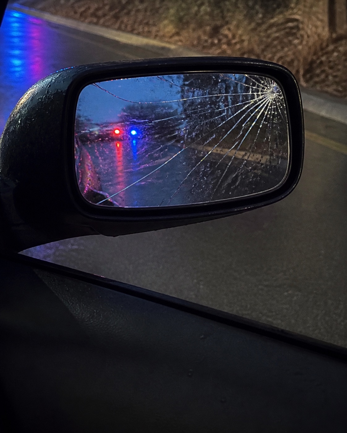 AI-generated illustration of a cracked mirror reflecting emergency lights. Not a real crash, case result or indication of injury severity.
